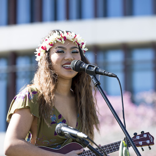 Student singing into mic with ukulele.